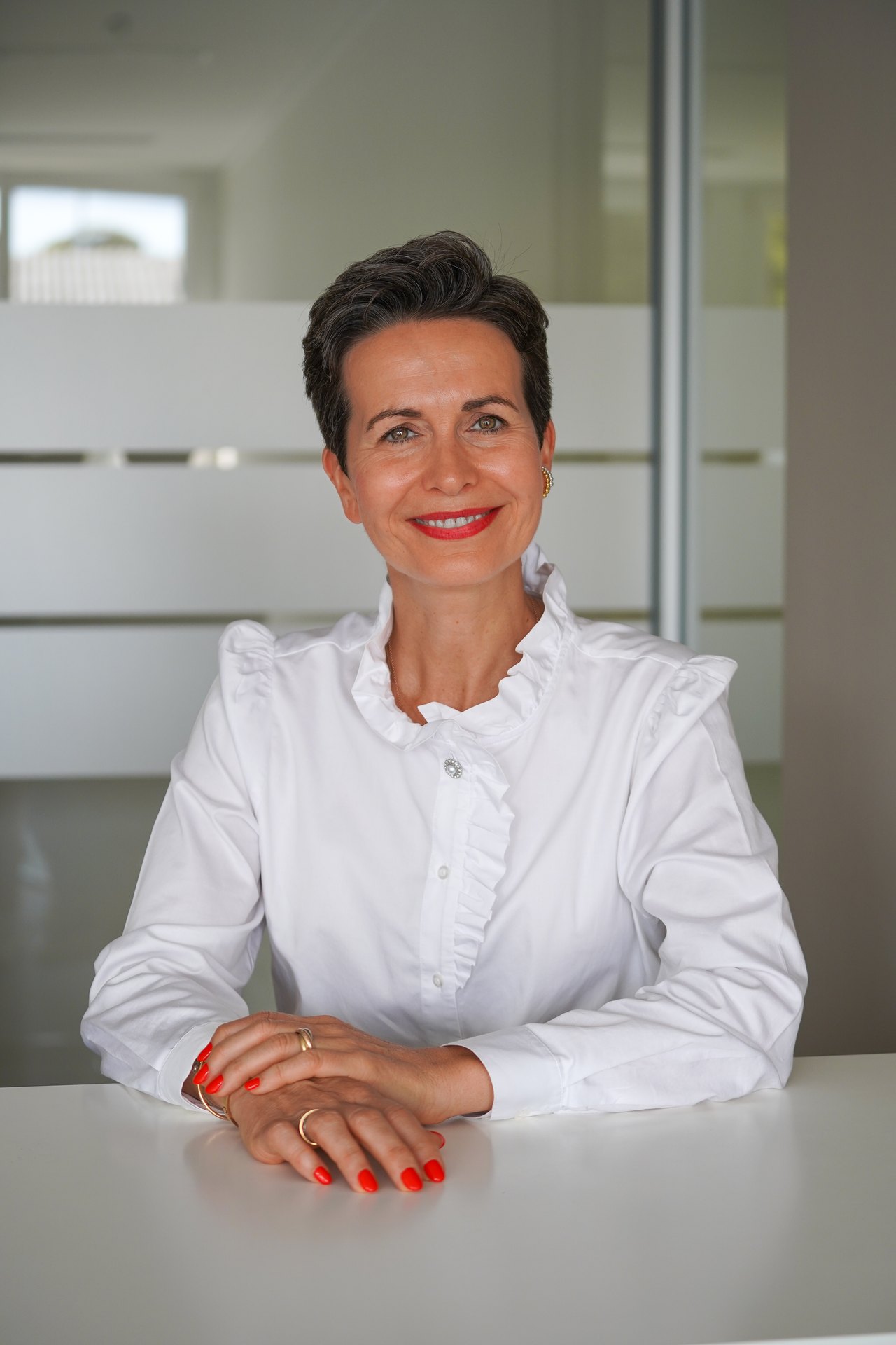 Shila Driesch am Tisch im Büro, lächelt in die Kamera
